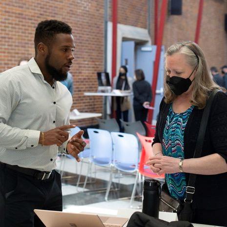 A masked woman talks with a man wearing a white shirt.